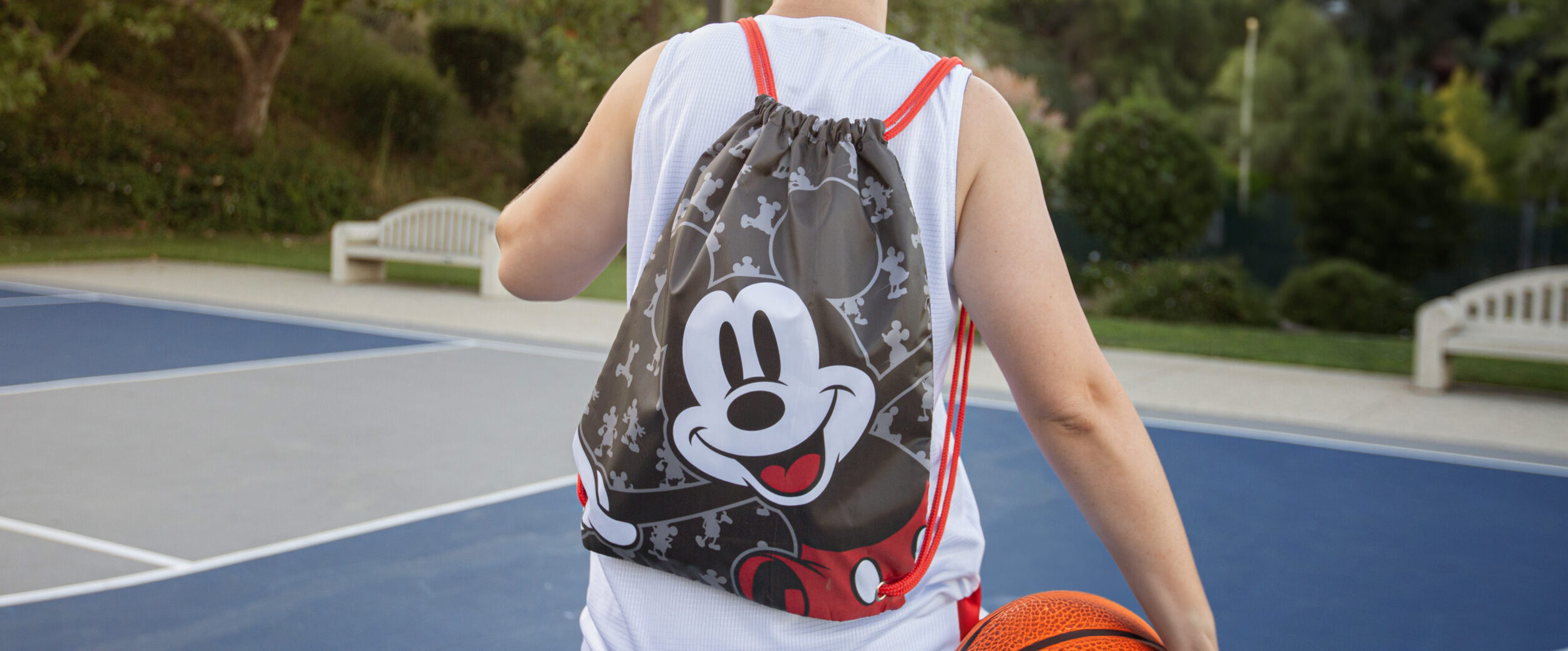 Man wearing a Mickey Mouse cinch bag at a basketball court
