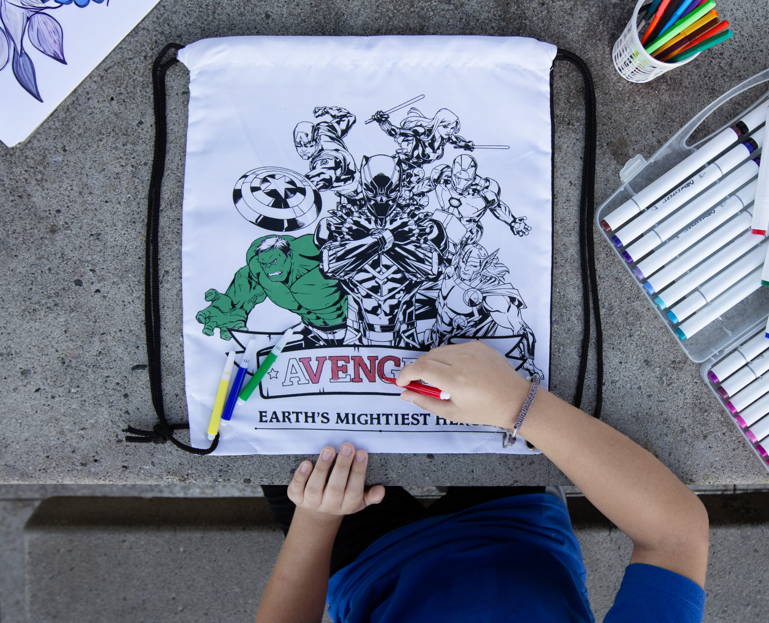 Kid coloring a Marvel's Avengers coloring cinch bag